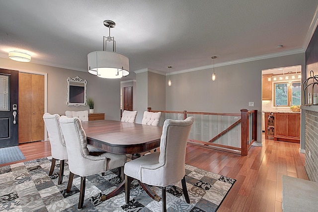 dining room with ornamental molding, a textured ceiling, and light wood-type flooring