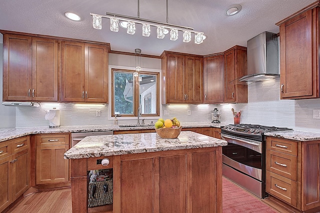 kitchen featuring a kitchen island, appliances with stainless steel finishes, sink, light stone counters, and wall chimney exhaust hood