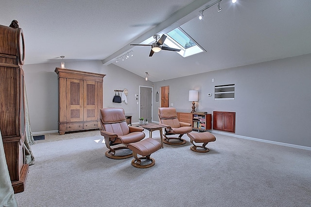 sitting room featuring ceiling fan, vaulted ceiling with skylight, track lighting, and light carpet