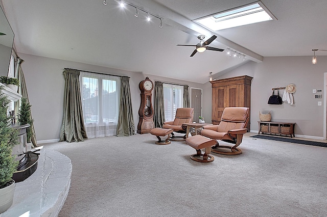 living area with lofted ceiling with skylight, light colored carpet, rail lighting, and ceiling fan