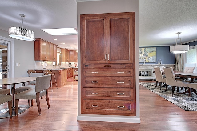 kitchen featuring hardwood / wood-style flooring, crown molding, a textured ceiling, and decorative light fixtures