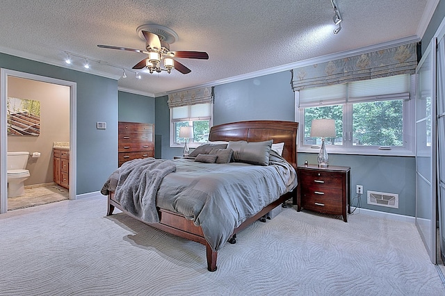 bedroom featuring crown molding, connected bathroom, light colored carpet, and a textured ceiling