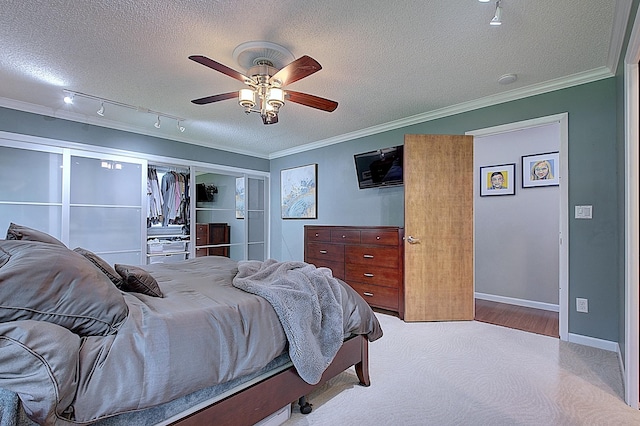 bedroom featuring ceiling fan, ornamental molding, track lighting, and a textured ceiling