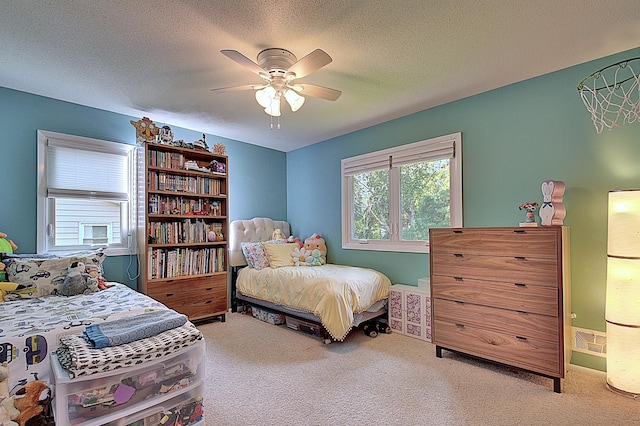 carpeted bedroom featuring ceiling fan and a textured ceiling