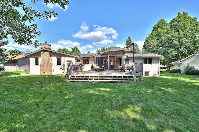 rear view of house featuring a lawn and a deck