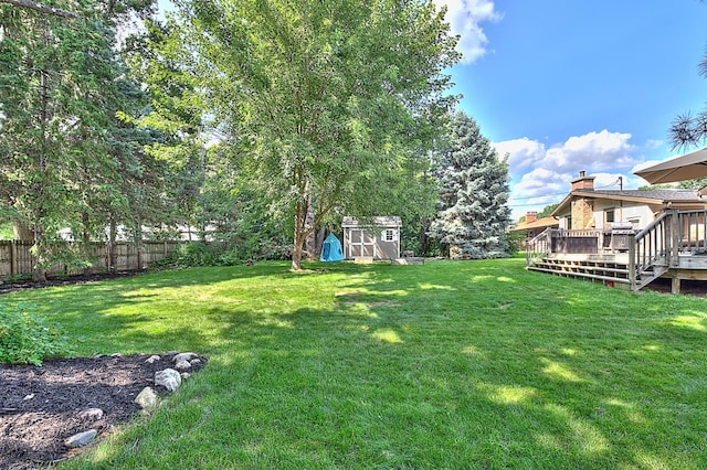 view of yard featuring a wooden deck and a storage unit