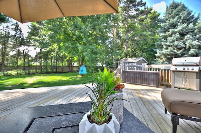 wooden terrace featuring an outdoor structure, area for grilling, and a lawn