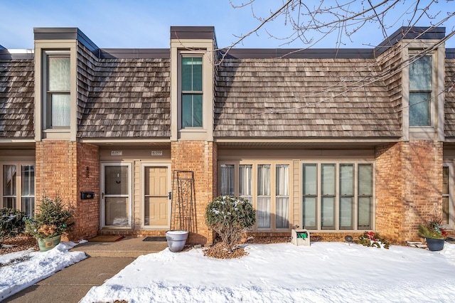 view of front of house with mansard roof and brick siding