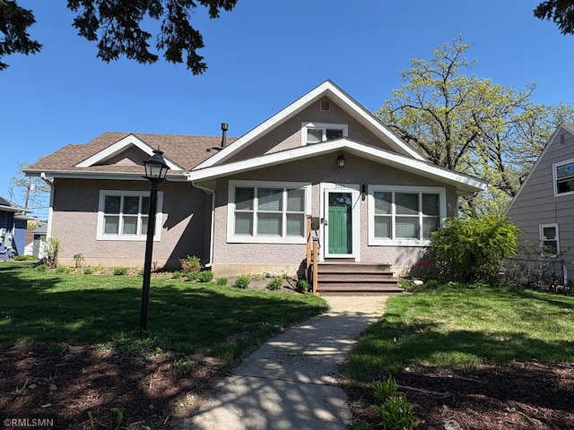 bungalow with stucco siding, fence, and a front yard