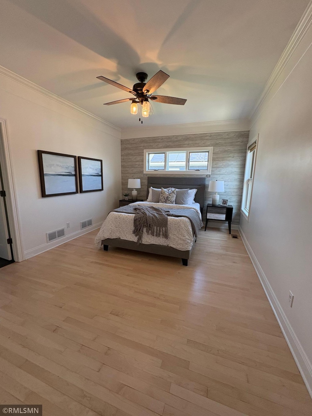 bedroom with crown molding, light wood-style floors, and visible vents