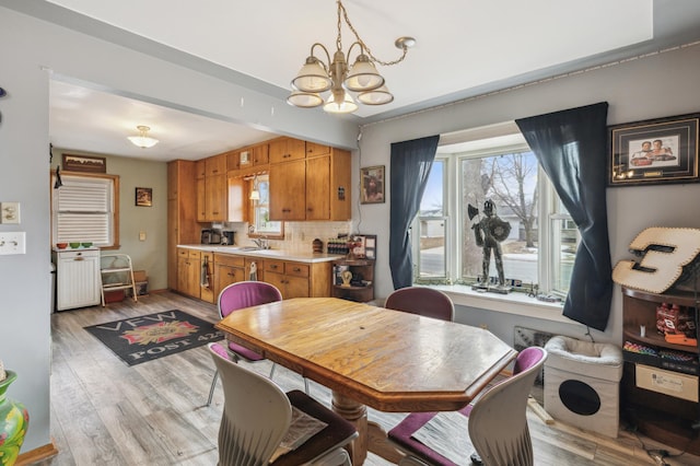 dining room with a notable chandelier, light hardwood / wood-style floors, and sink