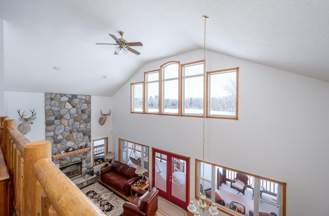 living room featuring ceiling fan, lofted ceiling, and a stone fireplace