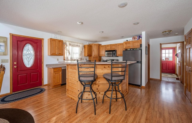 kitchen featuring a breakfast bar area, a center island, light hardwood / wood-style floors, stainless steel appliances, and plenty of natural light