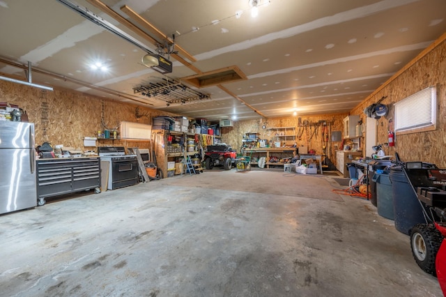 garage featuring stainless steel refrigerator, a garage door opener, and a workshop area