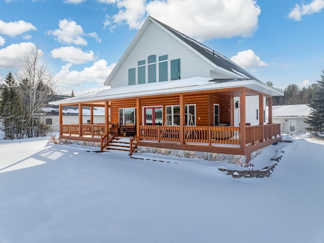 snow covered back of property with covered porch