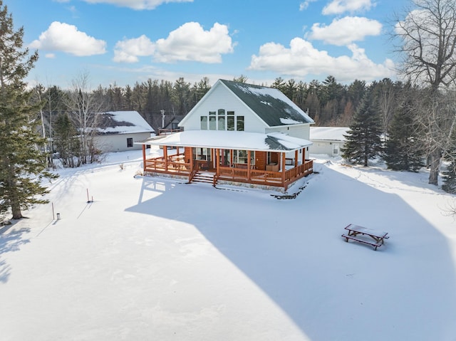 snow covered back of property with covered porch