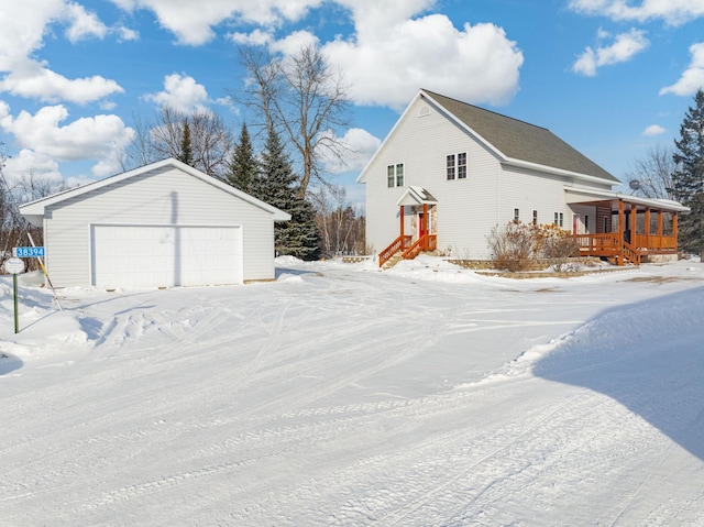 view of snow covered exterior featuring an outbuilding and a garage