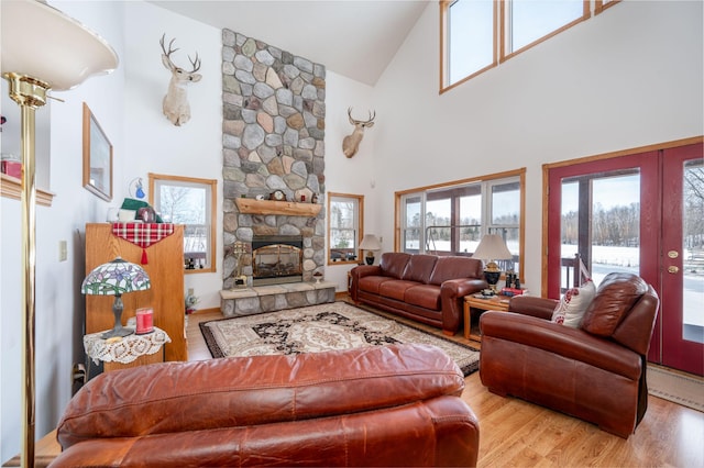 living room with french doors, high vaulted ceiling, a fireplace, and light hardwood / wood-style flooring