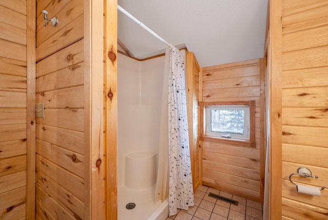 bathroom featuring lofted ceiling, wooden walls, curtained shower, and tile patterned flooring