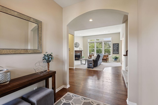 hallway with baseboards, arched walkways, hardwood / wood-style floors, and recessed lighting