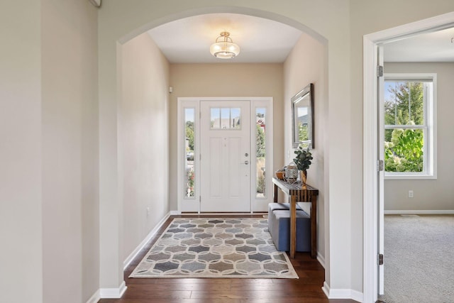 entryway with baseboards, arched walkways, and hardwood / wood-style floors