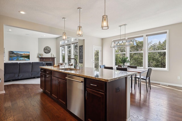 kitchen with dark wood-type flooring, a fireplace, a sink, and stainless steel dishwasher