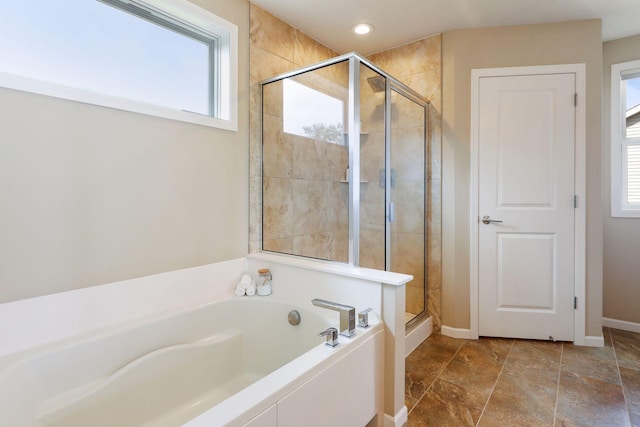 bathroom with a garden tub, a shower stall, plenty of natural light, and baseboards