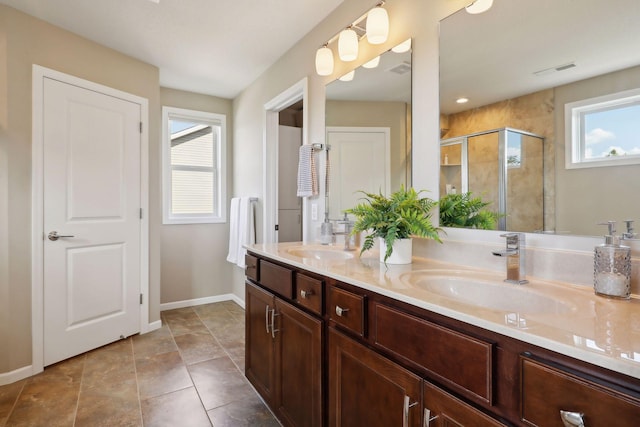 bathroom featuring a stall shower, a healthy amount of sunlight, and a sink