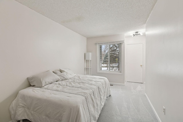 bedroom featuring a textured ceiling, baseboards, and light carpet