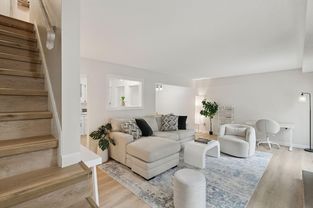 living area featuring stairway, baseboards, and wood finished floors