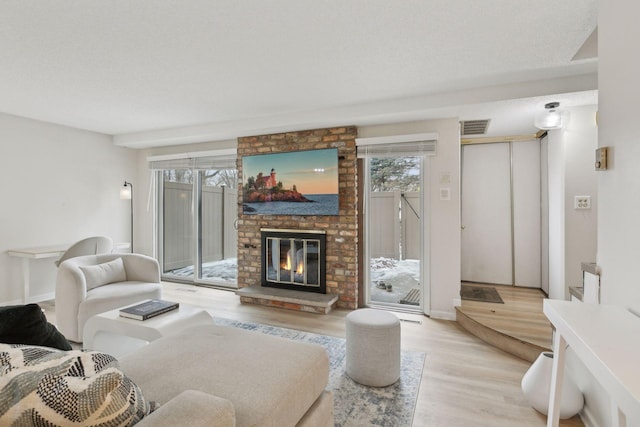 living room featuring visible vents, a fireplace, and wood finished floors