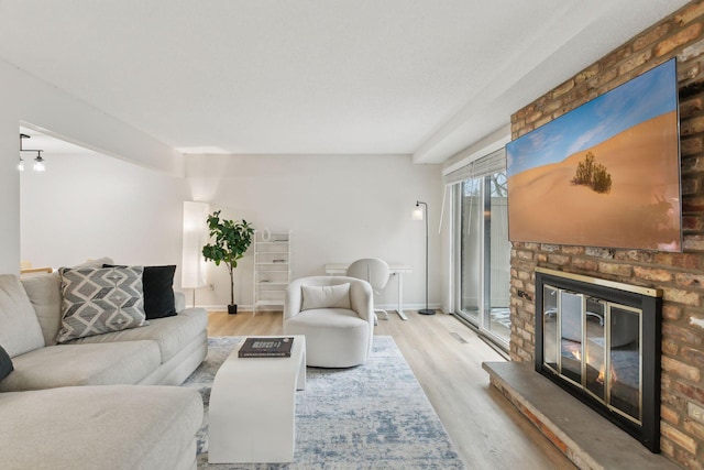 living area featuring a glass covered fireplace, baseboards, and wood finished floors