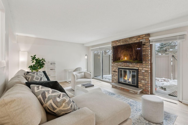 living area featuring a brick fireplace, wood finished floors, and baseboards