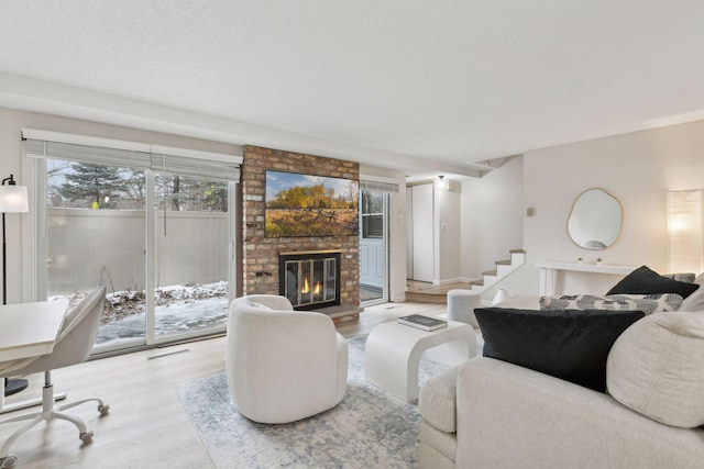 living area with visible vents, a brick fireplace, stairs, and wood finished floors