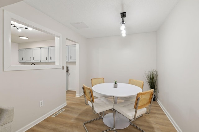 dining room featuring visible vents, light wood-type flooring, and baseboards