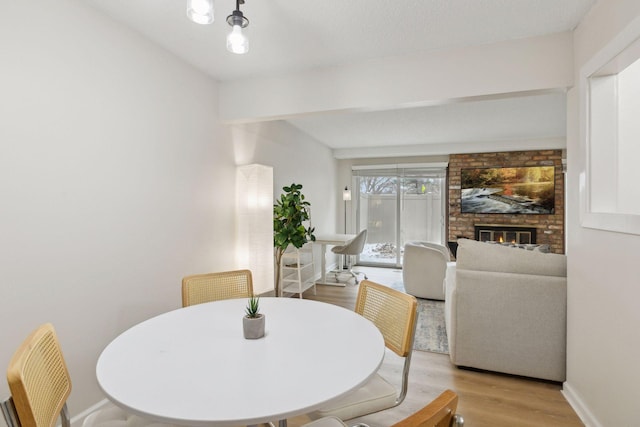 dining space featuring a fireplace, baseboards, and wood finished floors