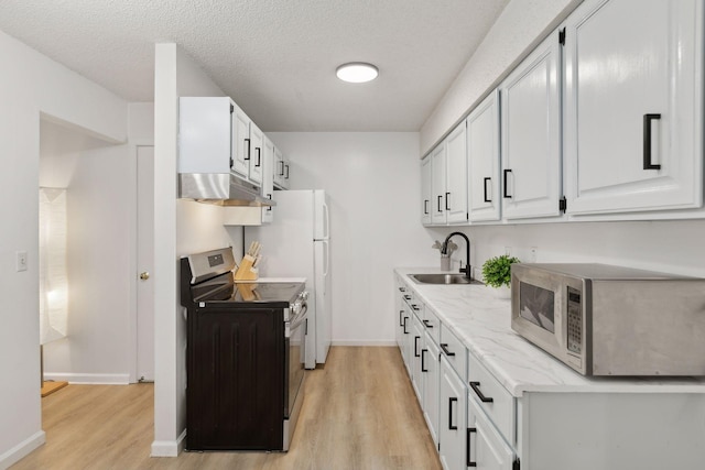 kitchen featuring a sink, under cabinet range hood, a textured ceiling, appliances with stainless steel finishes, and light wood-type flooring