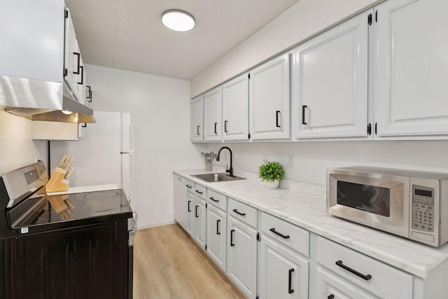 kitchen featuring light wood-style flooring, range with electric cooktop, a sink, white cabinets, and exhaust hood