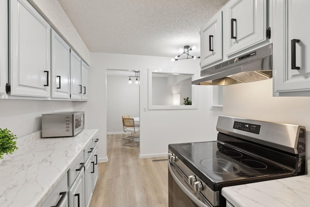 kitchen with stainless steel appliances, white cabinets, light wood-style floors, under cabinet range hood, and a textured ceiling