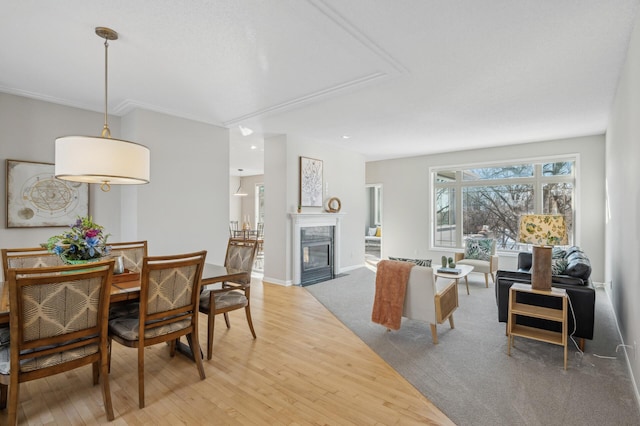 dining space with wood finished floors, a fireplace with flush hearth, and baseboards