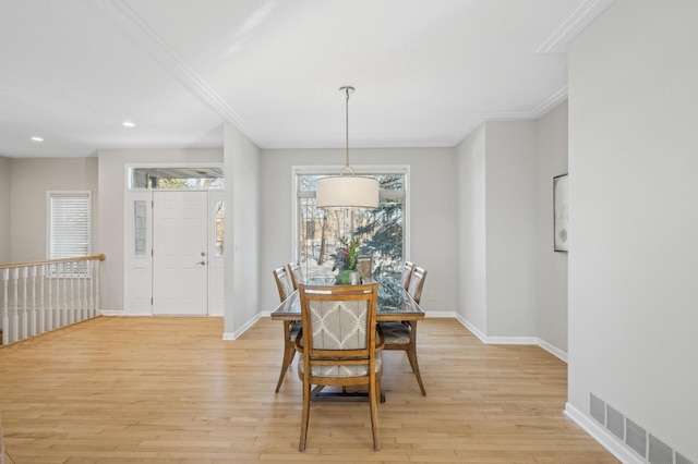 dining room with crown molding, light wood finished floors, visible vents, and baseboards