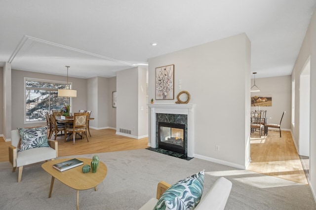 living area featuring light carpet, baseboards, visible vents, a premium fireplace, and recessed lighting