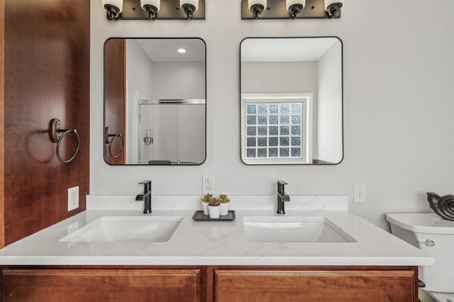 full bath featuring double vanity, a sink, and a shower with shower door