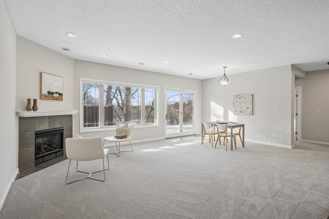 living area featuring a fireplace, baseboards, a textured ceiling, and light colored carpet