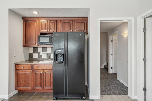 kitchen featuring tasteful backsplash, dark colored carpet, light countertops, a sink, and black appliances