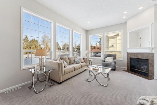 carpeted living area with plenty of natural light, a fireplace, visible vents, and baseboards