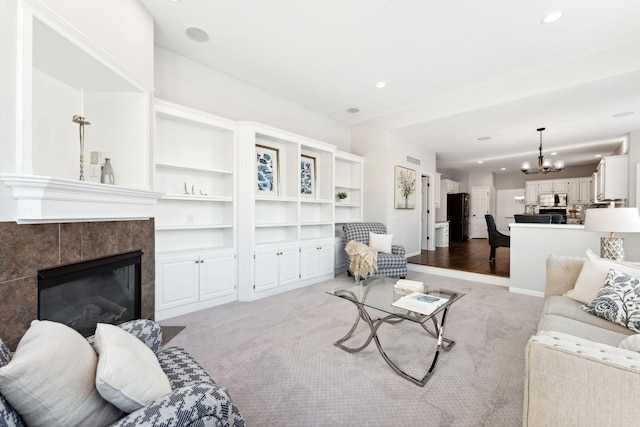 living room with recessed lighting, light colored carpet, a fireplace, and an inviting chandelier