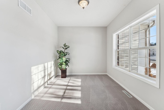 empty room featuring carpet floors, visible vents, and baseboards