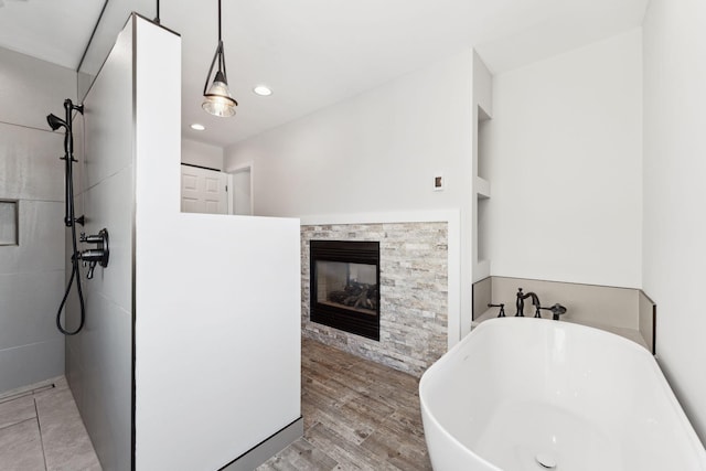 bathroom featuring wood finished floors, a soaking tub, a multi sided fireplace, and a walk in shower