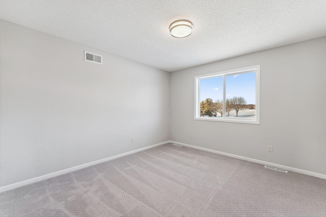 carpeted empty room with visible vents, baseboards, and a textured ceiling